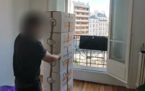 Déménageur DEMEX déplaçant une pile de cartons sur un diable