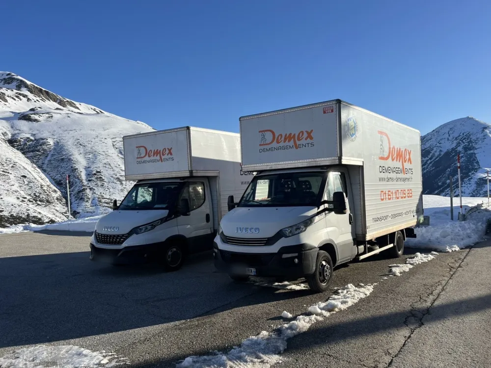 Deux camions DEMEX Déménagements à la frontière d'Andorre, montagnes enneigées, pour un déménagement longue distance