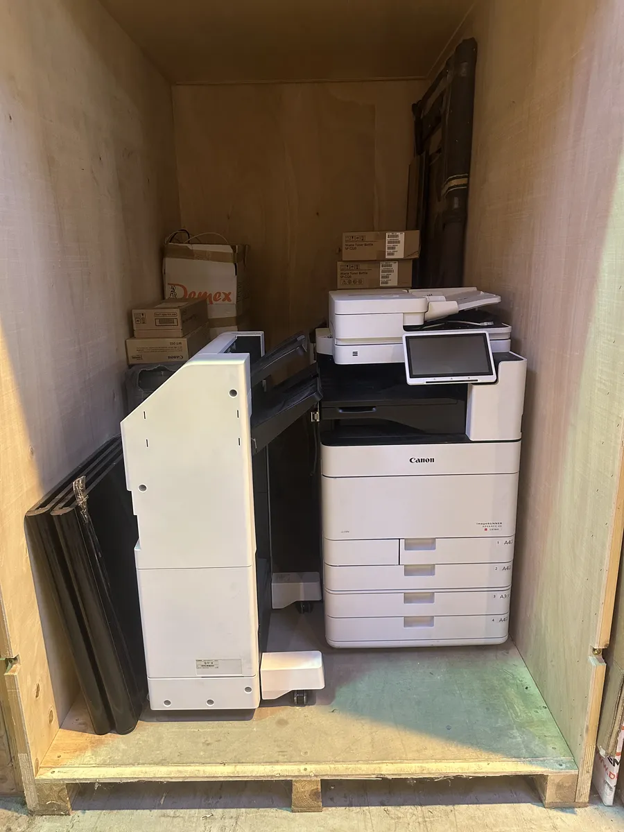 Copieur Canon et son module de finition stockés dans un conteneur de garde-meubles DEMEX, cartons de consommables à côté