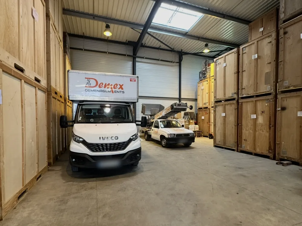 Garde-meubles DEMEX : camion dans l'entrepôt entre les conteneurs de stockage en bois