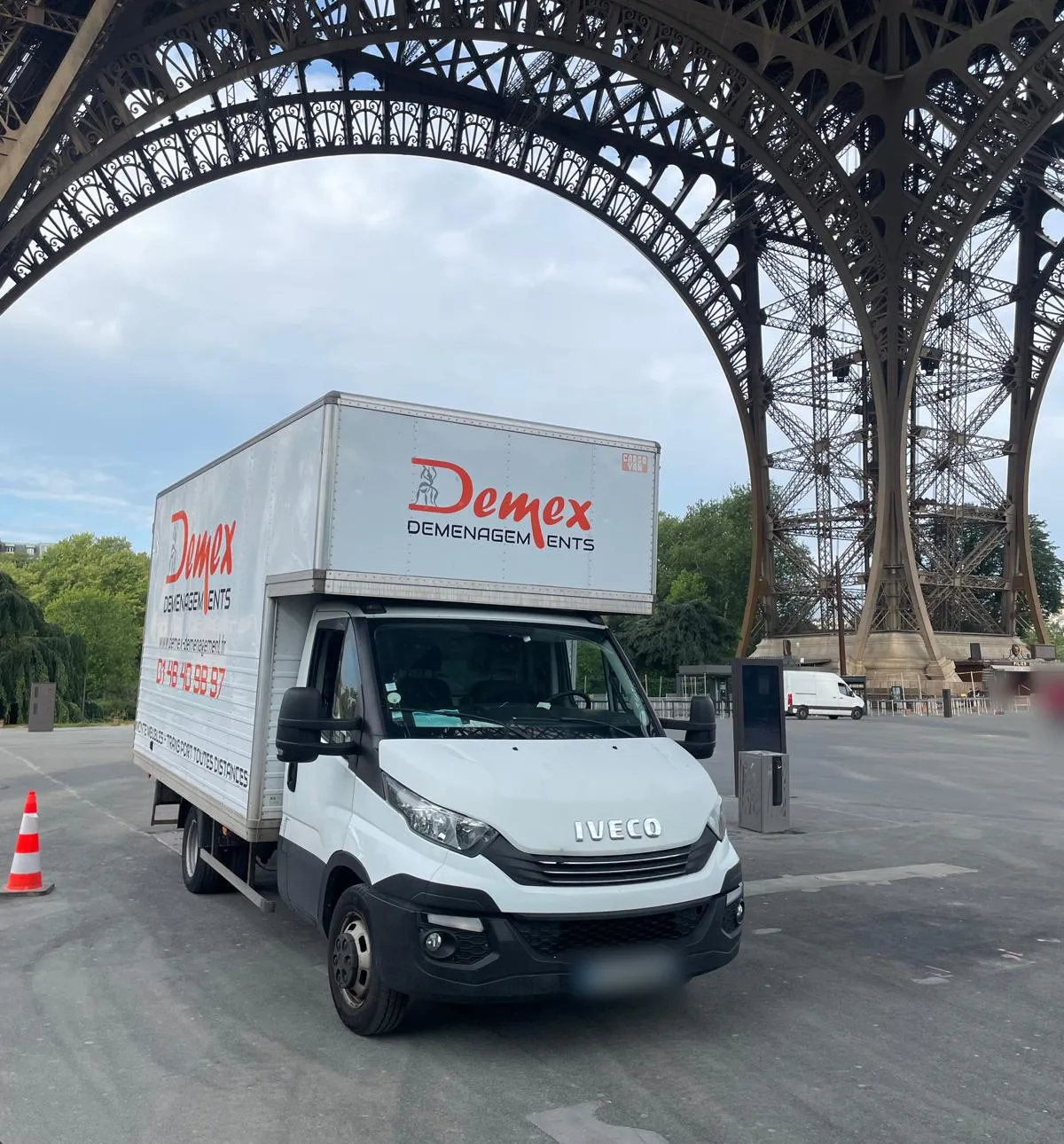 Camion DEMEX Déménagements stationné sous l'arche de la tour Eiffel à Paris
