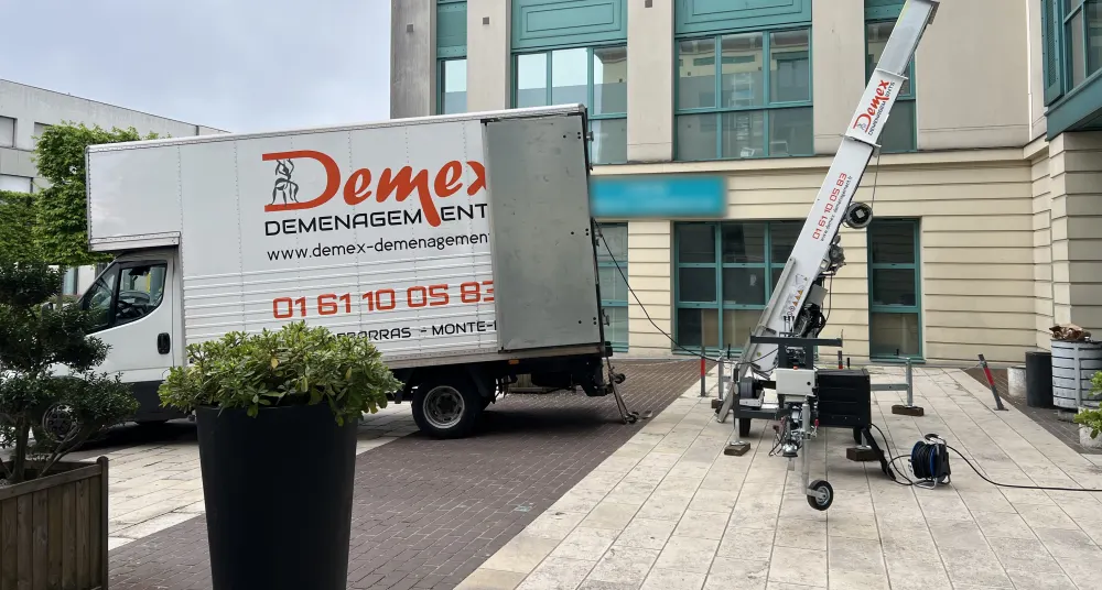 Camion DEMEX et monte-meubles déployé devant un bâtiment pour une intervention en étage