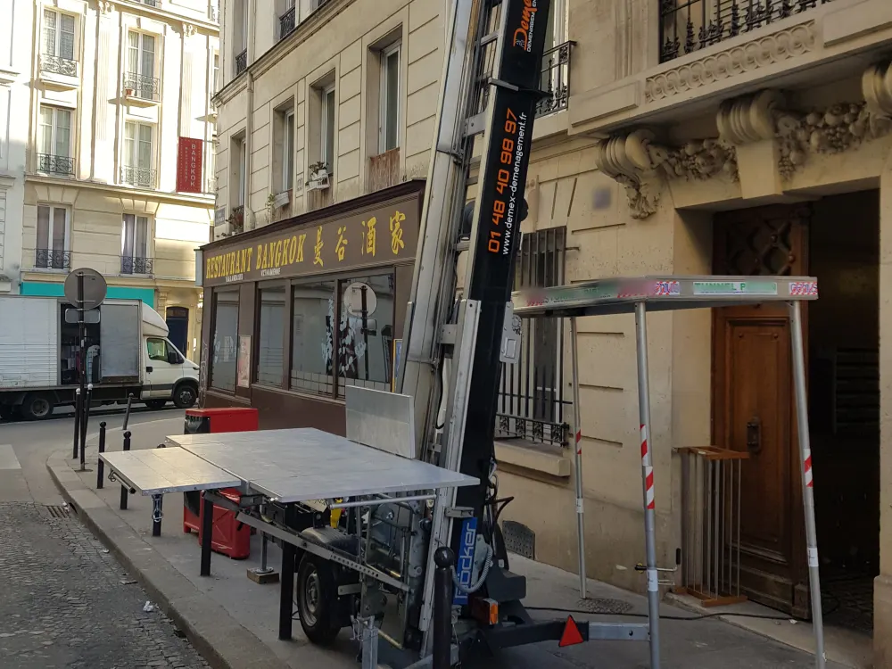 Monte-meubles DEMEX installé dans une rue de Paris avec tunnel de protection pour les piétons