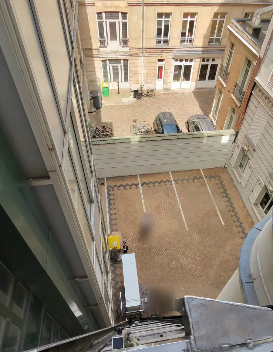 Vue depuis le haut du monte-meubles sur une cour d’immeuble parisien, plateau et commandes au premier plan